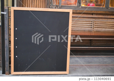 Empty wooden blackboard mockup standing outdoors in front of cafe Empty wooden blackboard mockup standing outdoors in front of cafe 113040691