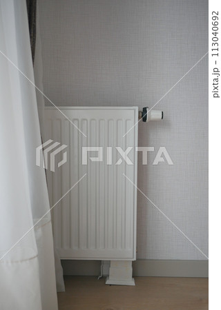 White radiator on grey white wall. apartment heating installation system,  113040692