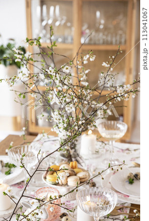 Spring Easter decor. Easter table setting. Flowers and dishes and candles for a festive dinner 113041067