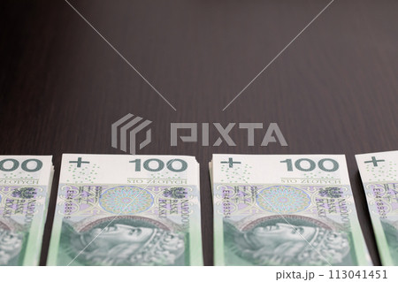 Banknotes evenly distributed on a dark brown desk ready for use. 113041451