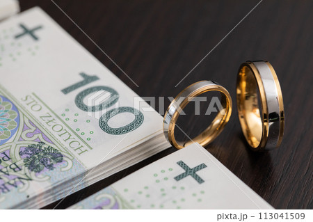 Gold wedding rings surrounded by a stack of Polish banknotes. Gold wedding rings surrounded by a stack of Polish banknotes. 113041509