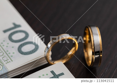 Gold wedding rings surrounded by a stack of Polish banknotes. Gold wedding rings surrounded by a stack of Polish banknotes. 113041511