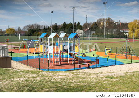 A playground for children to play. Colorful play sets and a safe surface. Coniferous tree branch with cones. Pine. 113041597