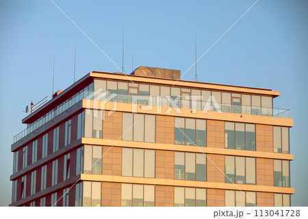 A high multi-family apartment block against a blue sky. A high multi-family apartment block against a blue sky. 113041728