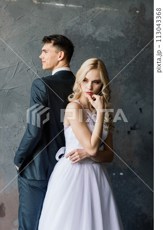 Cute wedding couple in interior of classic studio. They kiss and hug each other. Cute wedding couple in interior of classic studio. They kiss and hug each other. 113043368