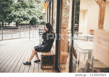 ベンチに座り飲み物を飲む女子高生 ベンチに座り飲み物を飲む女子高生 113043924