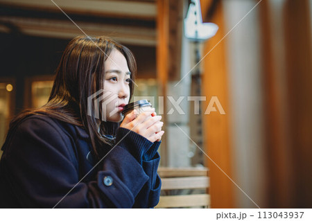 ベンチに座り飲み物を飲む女子高生 ベンチに座り飲み物を飲む女子高生 113043937