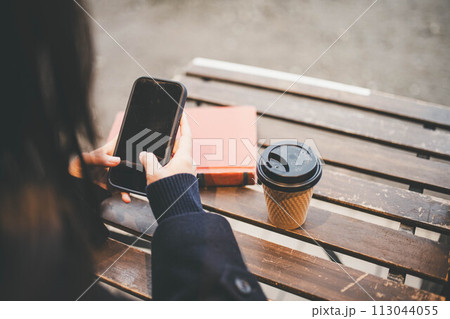 カフェで飲み物を飲みながらスマホをいじる女子高校生 カフェで飲み物を飲みながらスマホをいじる女子高校生 113044055
