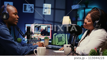 Online show host listening to guest opinion on current events during live broadcast for social media platforms. African american influencer using professional gear to record podcast, zoom in shot 113044228