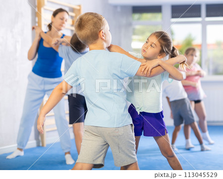 Boys and girls in gym perform basic elements of krav maga self-defense system. 113045529