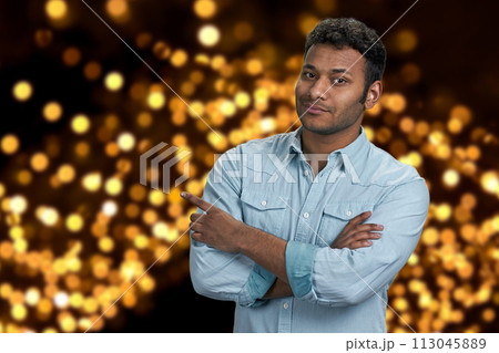 Handsome young man pointing with finger aside. Festive bokeh lights background. Christmas holiday deal. Handsome young man pointing with finger aside. Festive bokeh lights background. Christmas holiday deal. 113045889