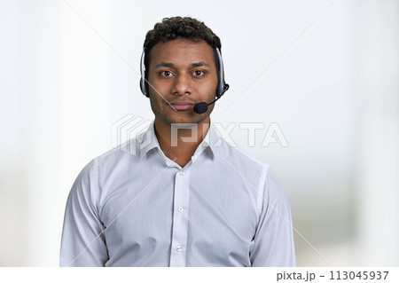 Handsome consultant of call center in headset looking at camera. Portrait of call center agent on blurred background. 113045937
