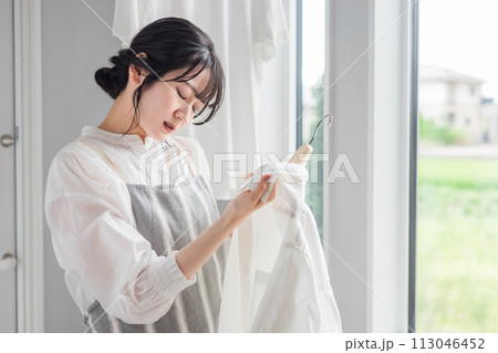 洗濯物のシャツの襟元の汚れに悩む主婦の女性（黄ばみ・漂白剤・洗剤・汗ジミ・汚れ） 113046452