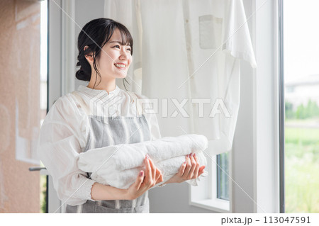 ランドリールーム・脱衣所で洗濯したバスタオルを持つ主婦の女性 ランドリールーム・脱衣所で洗濯したバスタオルを持つ主婦の女性 113047591