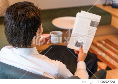 朝家やホテルで英字新聞を読むスーツ姿のアジア人ビジネスマン 113052728