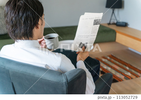 朝家やホテルで英字新聞を読むスーツ姿のアジア人ビジネスマン 113052729