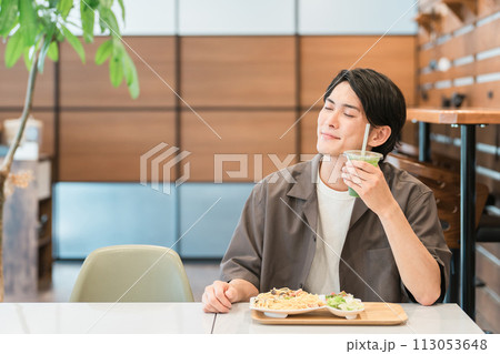 カフェでランチを食べながらグリーンスムージーを飲む若い男性（酵素・デトックス・食物繊維・健康食品） 113053648