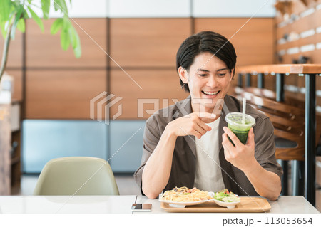 カフェでランチを食べながらグリーンスムージーを飲む若い男性(酵素・デトックス・食物繊維・健康食品) カフェでランチを食べながらグリーンスムージーを飲む若い男性(酵素・デトックス・食物繊維・健康食品) 113053654