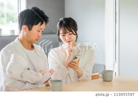 育児で困ってスマホで調べる若いアジア人夫婦 育児で困ってスマホで調べる若いアジア人夫婦 113055597