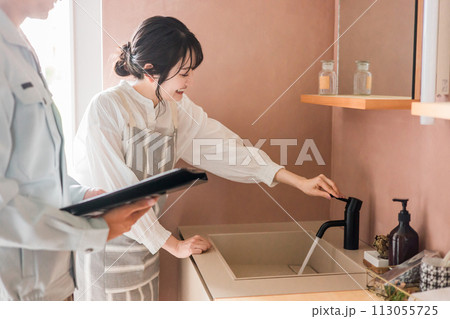 洗面所で水栓の作動確認をする主婦の女性と水道屋・設備屋の男性 113055725