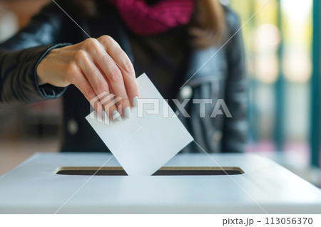 Close up of woman's hand dropping a ballot into a ballot box. 113056370