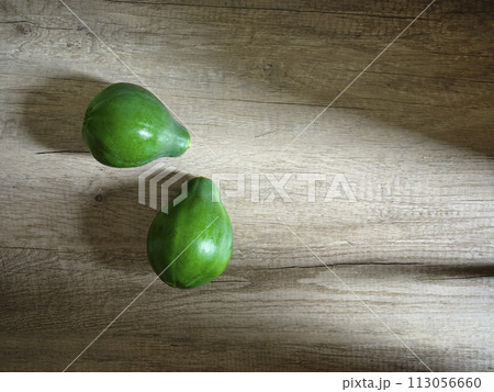 two green papayas on wooden surface two green papayas on wooden surface 113056660