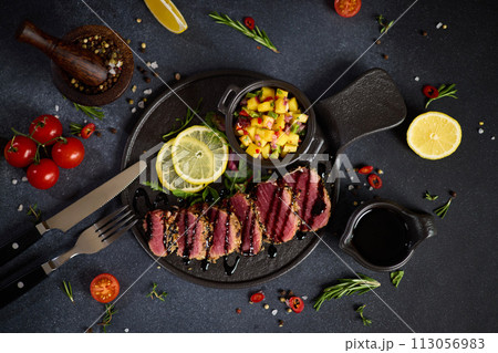 Sliced Organic grilled Tuna fillet covered with sesame seeds and mango salsa on black ceramic serving board Sliced Organic grilled Tuna fillet covered with sesame seeds and mango salsa on black ceramic serving board 113056983