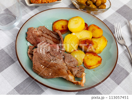 Delicious roasted beef steak with baked potato served with bread and olives 113057451