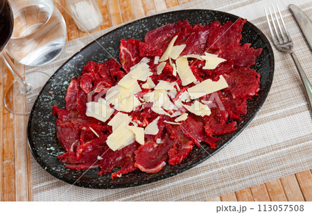 Beef carpaccio with slices of cheese on table 113057508