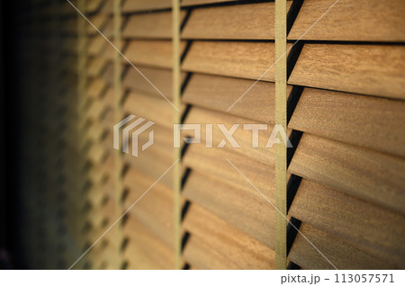 Close-up brown wooden blinds. lighting range control sunlight coming from a window. decoration interior. Modern jalousie. Close-up brown wooden blinds. lighting range control sunlight coming from a window. decoration interior. Modern jalousie. 113057571