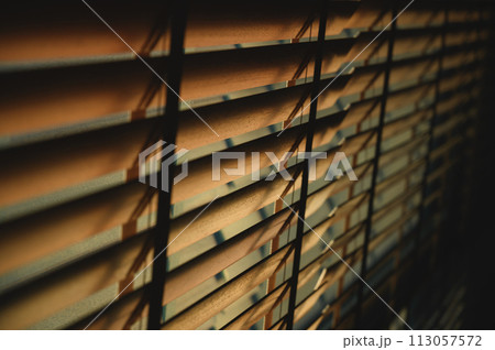 Close-up brown wooden blinds. lighting range control sunlight coming from a window. decoration interior. Modern jalousie. 113057572