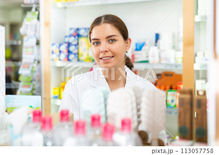 Portrait of a young female pharmacist standing behind the counter of a pharmacy 113057758