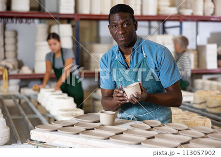 Man potter processing new crafted plates 113057902