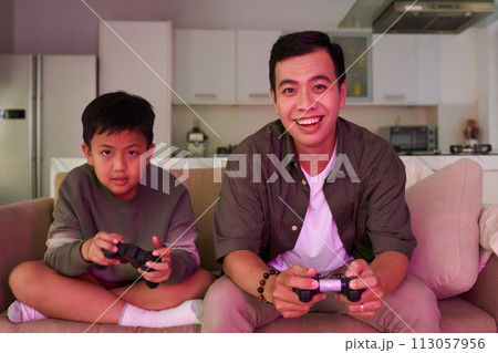 Excited father and son playing videogames at home 113057956