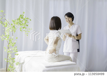 問診をするミドルエイジの女性整体師 113058499