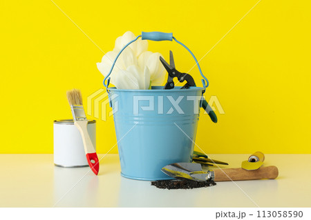 Gardening supplies, can of paint and tulips on yellow background 113058590