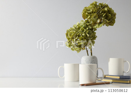 White cups with green hydrangeas in a vase 113058612