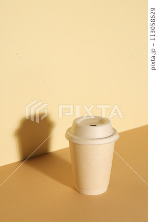 A paper cup with a lid on a light background 113058629