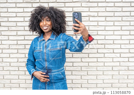 Radiant African American Woman Taking Selfie Against Textured Brick Wall Radiant African American Woman Taking Selfie Against Textured Brick Wall 113058870