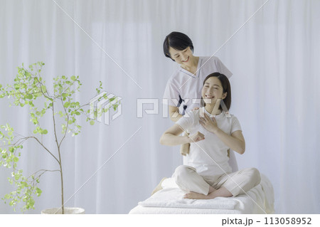 若い女性に施術をするミドルエイジの女性整体師 113058952