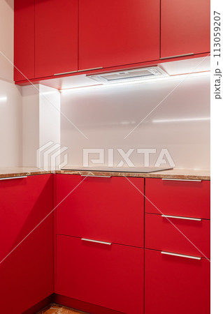 Minimalist kitchen corner with vibrant red cabinets and white walls Minimalist kitchen corner with vibrant red cabinets and white walls 113059207