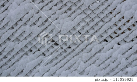 Snow sticking on a wire mesh fence, a fragment of fencing from a grate covered with a layer of wet fresh snow, a white texture graphic resource of winter with a geometric pattern Snow sticking on a wire mesh fence, a fragment of fencing from a grate covered with a layer of wet fresh snow, a white texture graphic resource of winter with a geometric pattern 113059929