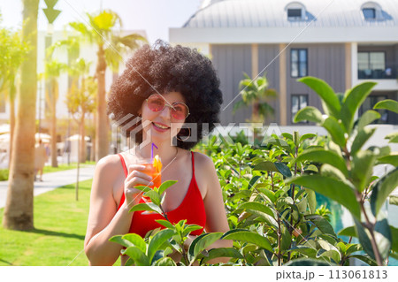 Adult woman with a toothy smile with curly hair drinks alcohol Adult woman with a toothy smile with curly hair drinks alcohol 113061813