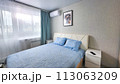 interior of the bedroom with a blue bedspread and pillows on the bed, a bedside table 113063209
