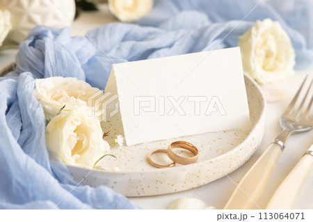 Folded Card near light blue tulle fabric and cream flowers on plate close up, copy space, wedding mockup Folded Card near light blue tulle fabric and cream flowers on plate close up, copy space, wedding mockup 113064071