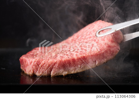牛もも肉のステーキを鉄板で焼く 113064306