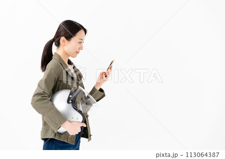 ヘルメットを抱えてスマートフォンを操作する女性 113064387