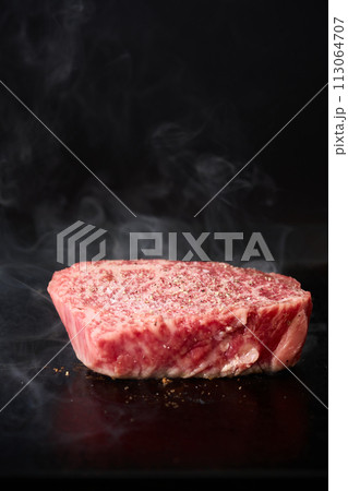 牛もも肉のステーキを鉄板で焼く 113064707