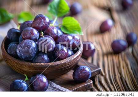 Wooden Bowl Filled With Purple Grapes on Wooden Table 113065343