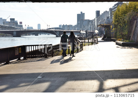 隅田川遊歩道を歩くカップル 113065715